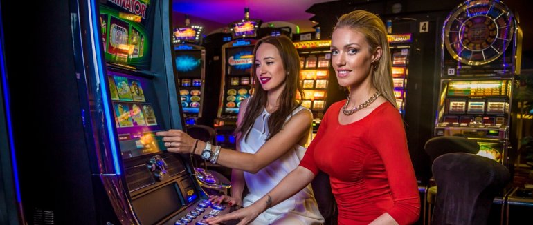 Две сексуальные подруги крутят барабаны на игровом автомате в дорогом казино