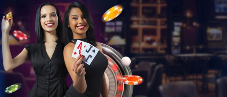Две привлекательные брюнетки позируют на фоне зала казино, держа карты и фишки