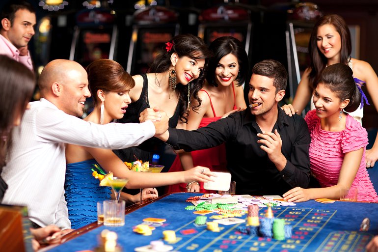 Мужчина выигравший в крэпс с сигарой в обществе других девушек пожимает руку другому игроку