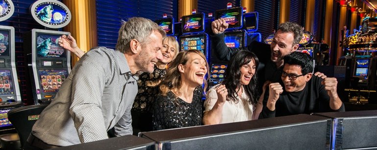 Азартная компания веселится за игрой на автоматах в казино Висбедан в Германии