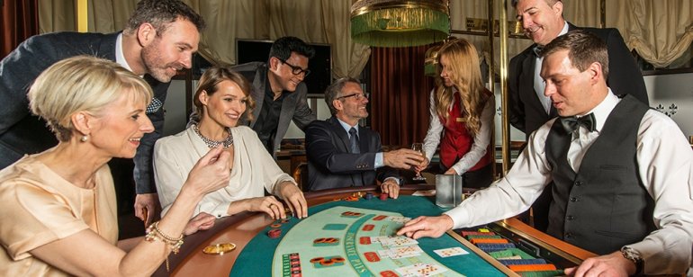 Женщины и мужчины в дорогих вечерних нарядах и строгих костюмах играют в компании профессионального крупье в казино Висбаден