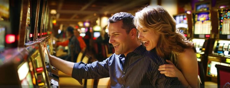 Счастливая пара играет на автомате в казино