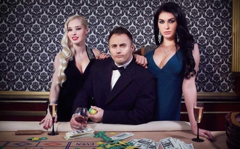 Богатый подкачанный мужчина в дорогом костюме отдыхает в казино в компании двух сексуальных подруг