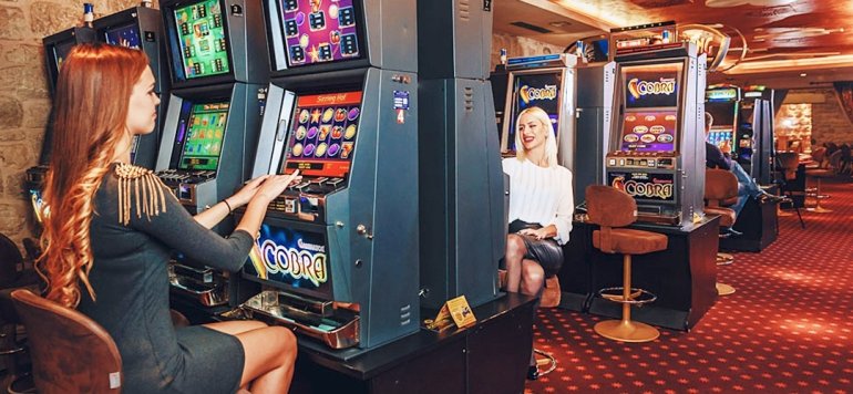 Две красотки играют на автоматах в зале казино
