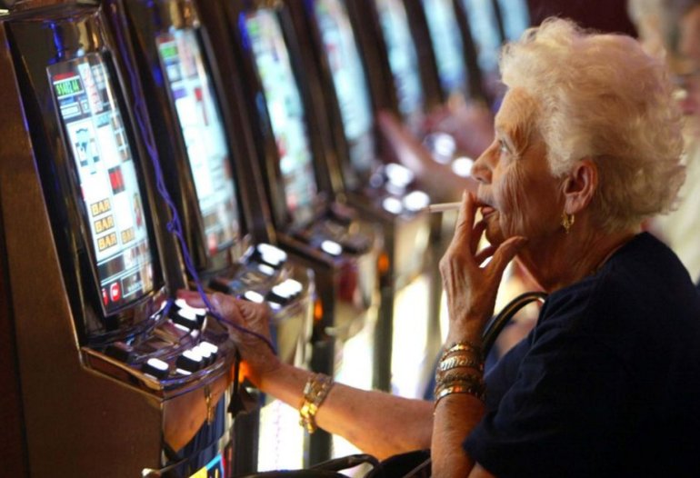Взрослая женщина с сигаретой играет в игровые автоматы