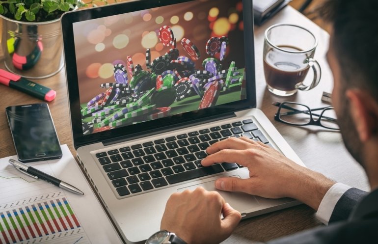 Обеспеченные молодой мужчина играет в онлайн казино в перерыве между работой