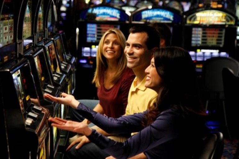 Мужчина и вдое женщин в хорошем настроении играют на слотах в казино