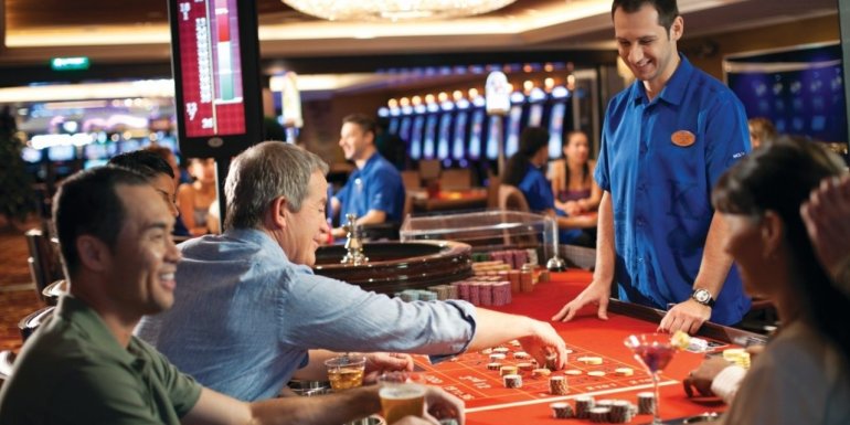 Азартные игроки совершают ставки в рулетке, а дилер сконцентрировано готовится к запуску шарика