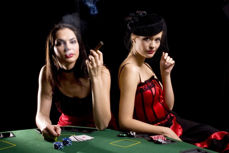 Две красотки в откровенных нарядах играют в казино, покуривая сигары