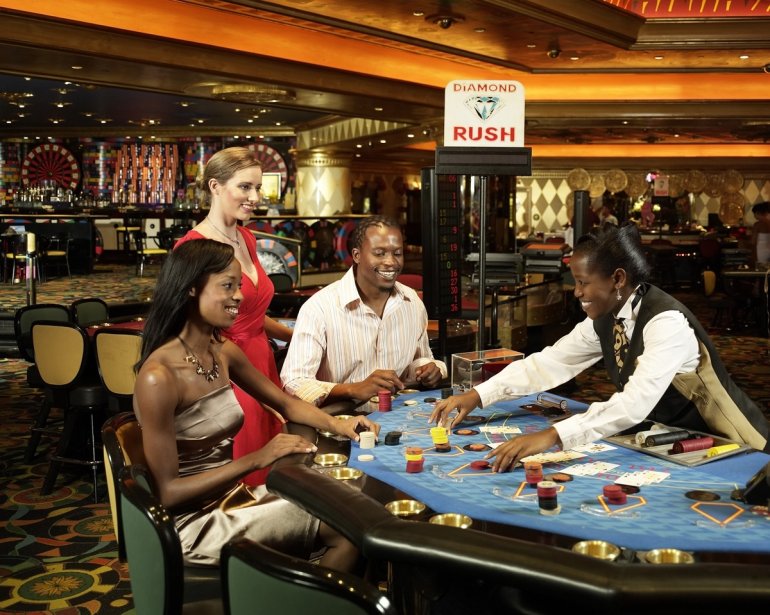Темнокожая девушка крупье ведет игру в блэкджек для гостей казино на Гаити